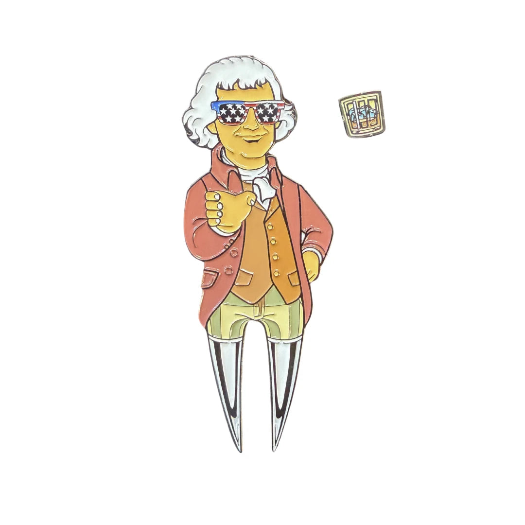 A cartoon in 18th-century attire with star-spangled sunglasses gives a thumbs up by a drink, highlighting the Grunk Dolfer Jefferson Divot Tool with magnetic ball marker clipped to its waist.