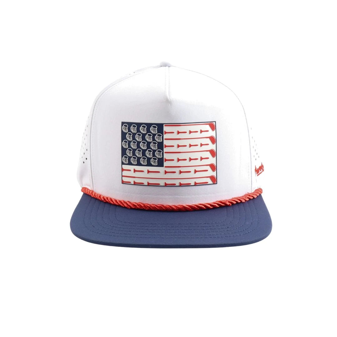 The Grunk Dolfer Grunk Flag Hat is a white golf hat with a blue brim, red rope detail, and an American flag patch on the front featuring golf icons in place of stars and stripes.