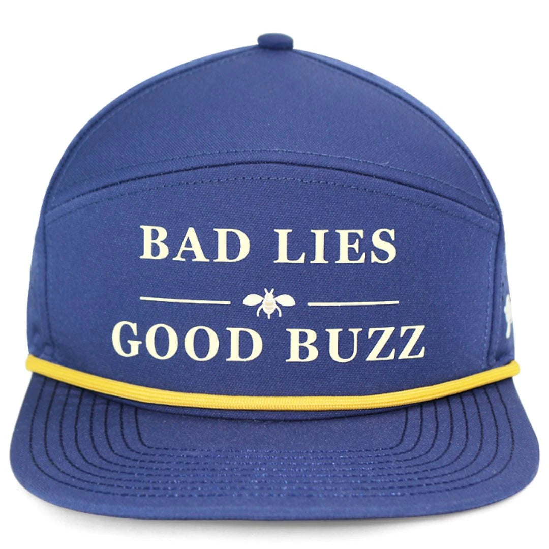 The Bad Lies Good Buzz Hat by Grunk Dolfer is a blue golf cap with white BAD LIES GOOD BUZZ text, a bee graphic, and a thin yellow band on the brim—ideal for any drinking club.