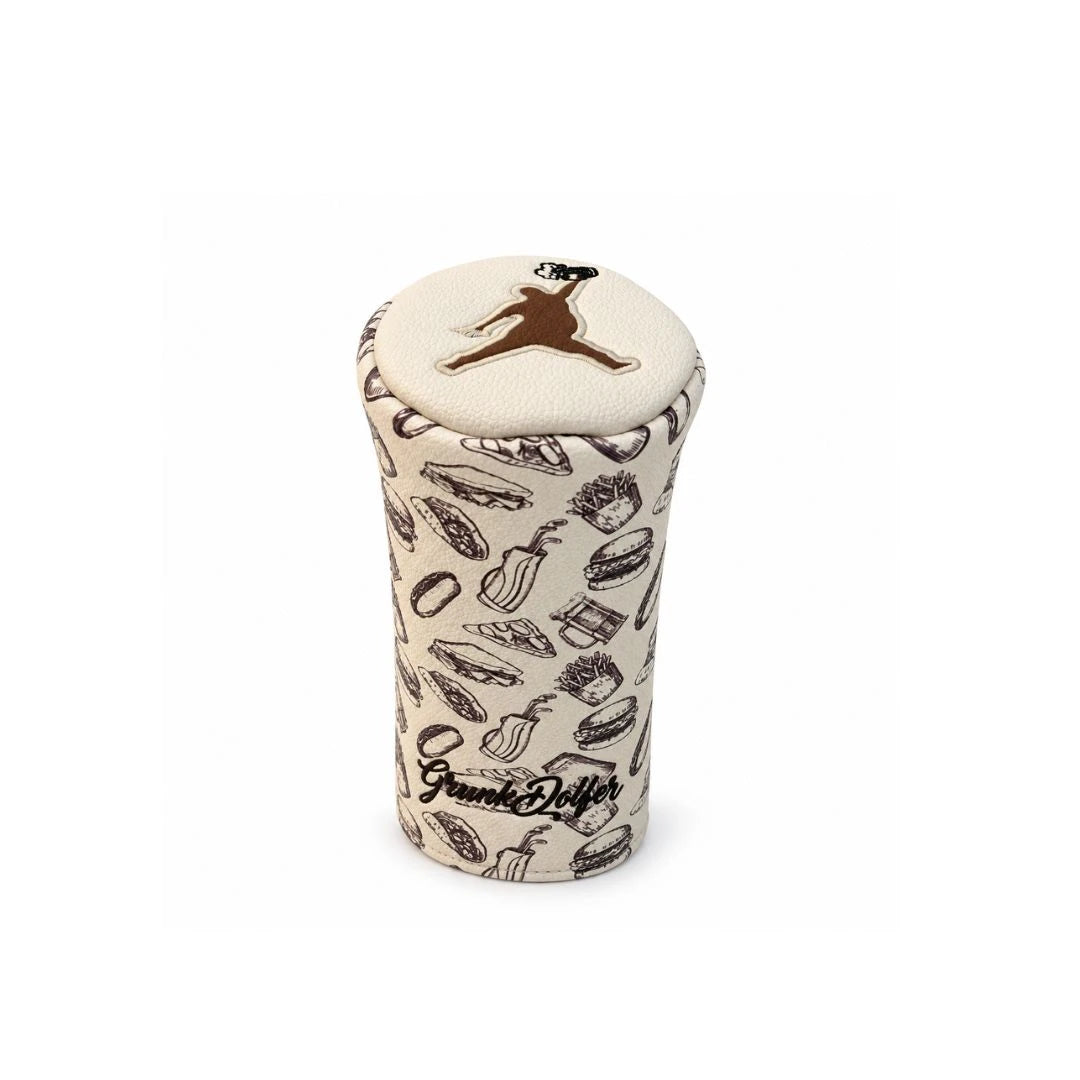 The Brown Chunkman Barrel Fairway Wood Cover by Grunk Dolfer is a cream-colored, cylindrical headcover made from premium faux leather, adorned with brown food illustrations and a brown leaping figure on top, with “Grunk Dolfer” scripted near the bottom—an eye-catching addition to any golf collection.