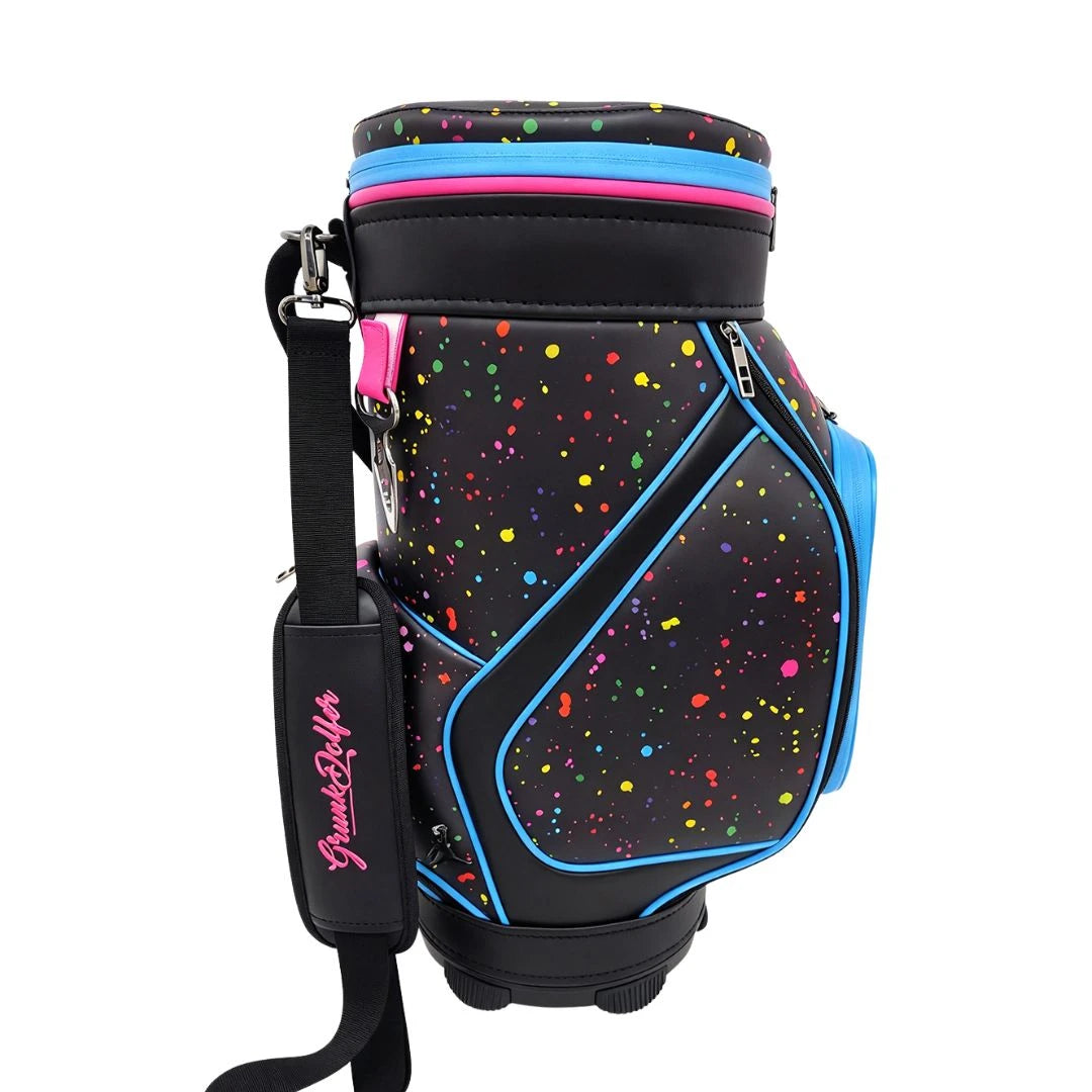 Black Grunk Dolfer Splatter Den Caddy golf bag featuring a colorful paint splatter pattern, bright blue and pink accents, and a matching shoulder strap.