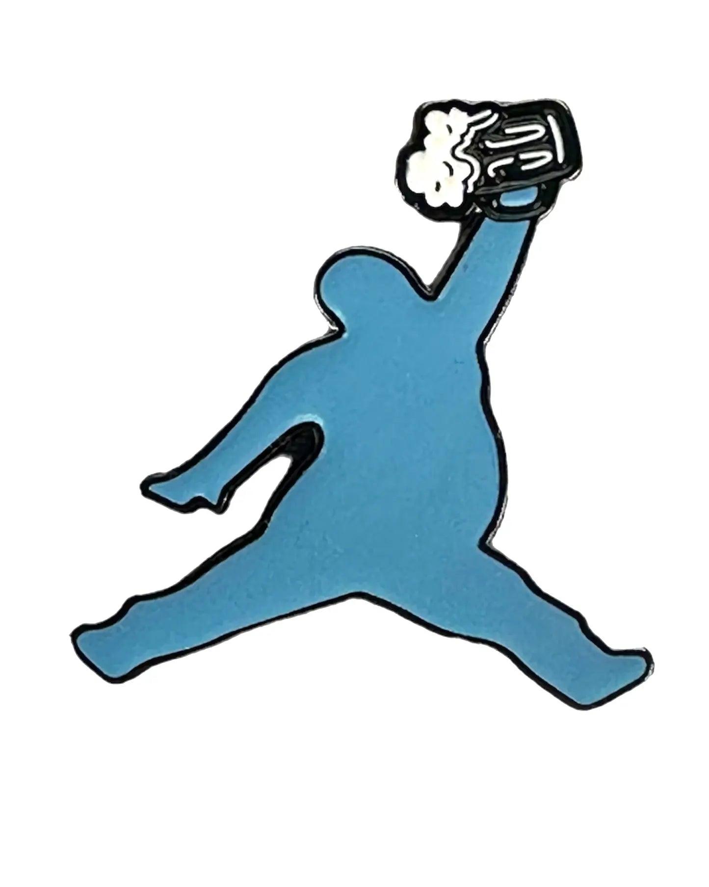 A blue silhouette of a person jumping, holding a frothy beer mug instead of a basketball—the ChunkMan Ball Marker by Grunk Dolfer is perfect for fans of funny golf accessories or unique golf gifts.