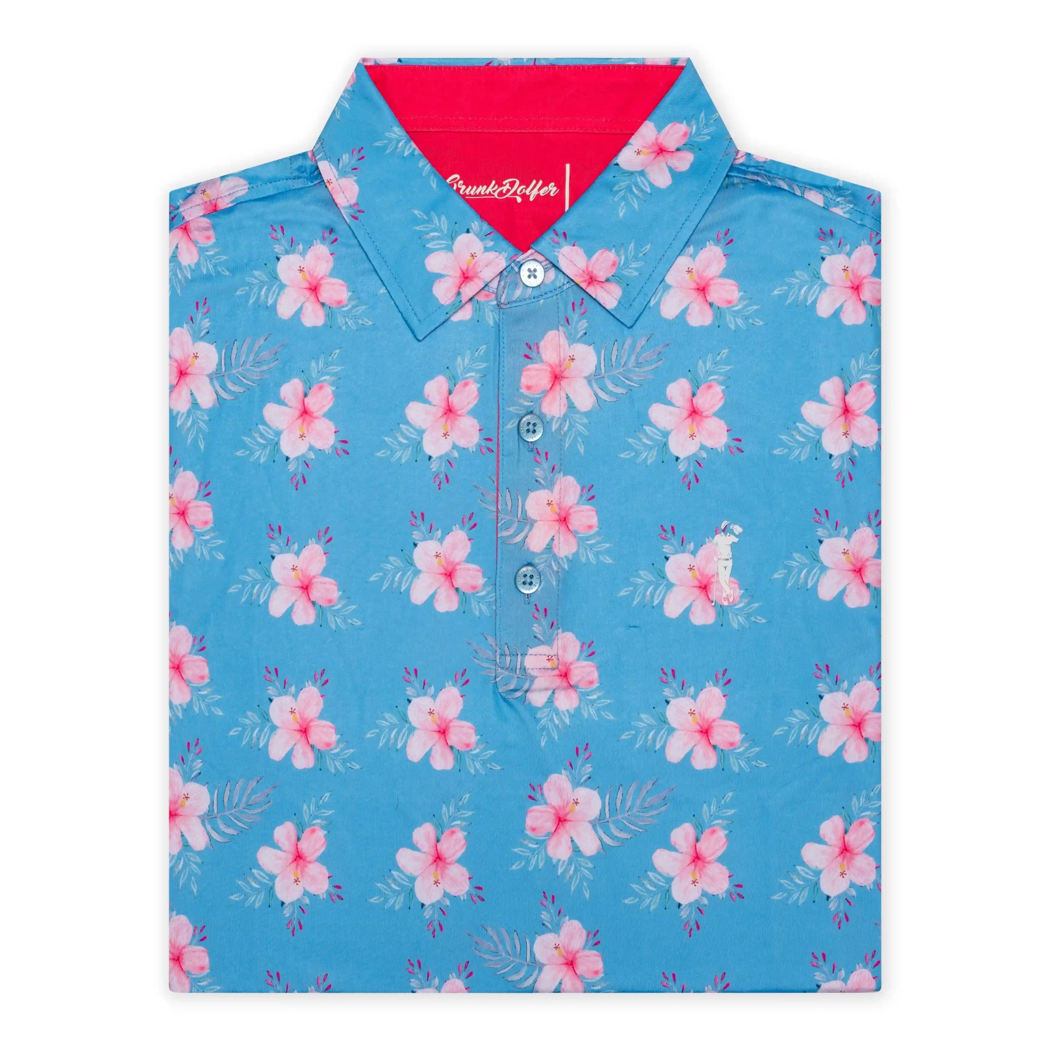 The Grunk Dolfer Hibiscus Hitter is a folded blue collared golf shirt, inspired by Hawaii, with pink and white hibiscus flowers, green leaves, and a bright red inner collar.