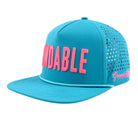 The Blue Findable Hat by Grunk Dolfer is a bright turquoise snapback with KINDABLE in large pink letters, side ventilation holes, “Grunk Dulux” in pink script, waterproof fabric, and a ball marker holder for golfers.