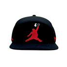 The Grunk Dolfer Black ChunkMan Hat is a moisture-wicking snapback featuring a bold red silhouette of a basketball player jumping with a burger, inspired by the classic Air Jordan logo—perfect for sporty style with a twist.
