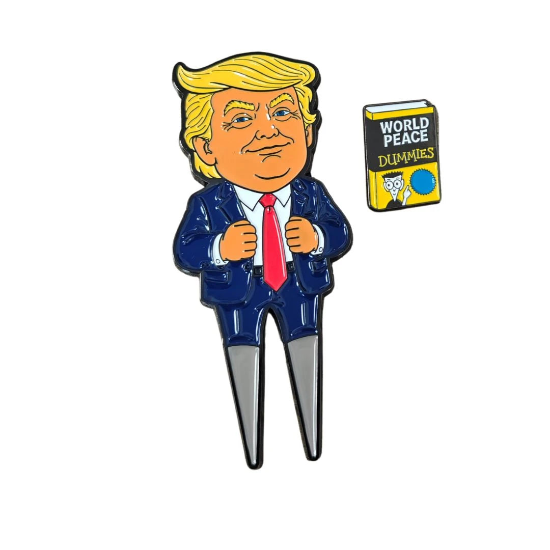A cartoon figure in a suit with yellow hair stands beside a small illustrated book titled World Peace for Dummies, featuring a yellow cover and a small owl drawing, while holding the Grunk Dolfer Trump Divot Tool with magnetic ball marker—a must-have accessory for any golf enthusiast looking to repair divots in style.