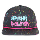The Black Splatter Hat by Grunk Dolfer features colorful paint, blue and pink GRUNK DOLFER graffiti on the front, and a thin pink rope above the brim—a bold choice for golfers.