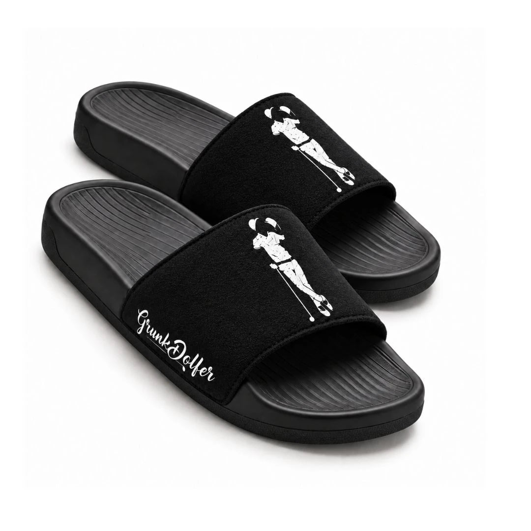Pair of black Grunk Dolfer Black Suede slides featuring a white golfer silhouette graphic on the straps, script text on the side, and a comfortable molded footbed.
