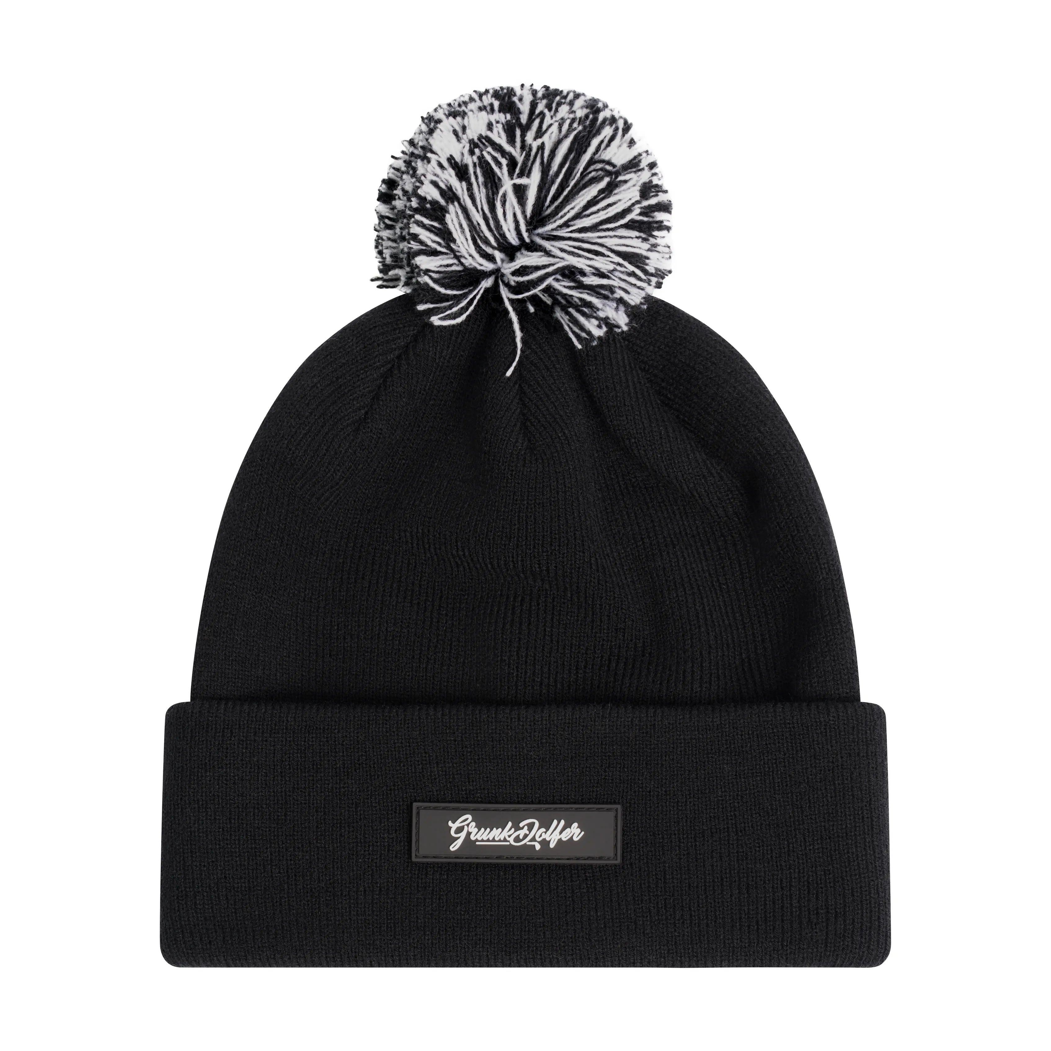 The Grunk Dolfer Bad Shots Beanie is a black acrylic hat with a turn-up cuff, topped by a black-and-white pom-pom and finished with a rectangular patch featuring white script text.