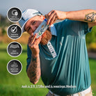 A bearded man, age 59, 175 lbs, wears a medium Grunk Dolfer Minty Palm golf shirt with UV protection, moisture wicking, zero wrinkles, and Dad Bod Approved icons, holding a can of Corona to his mouth while on the grass.